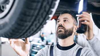 Delphi Technologies Expert standing underneath a vehicle, inspecting the wheel.